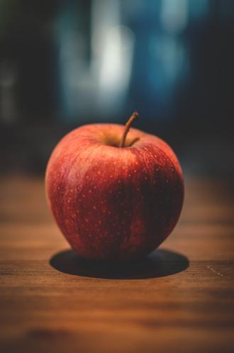 عکس سیب قرمز روی میز چوبی