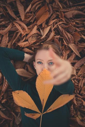 دختر چشم آبی کنار برگ های زرد پاییز
