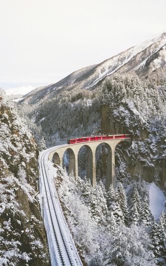 قطار قرمز در کوه پوشیده از برف